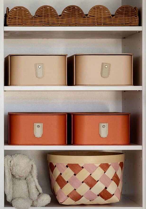 A shelf of scalloped baskets, labelled boxes and a soft toy