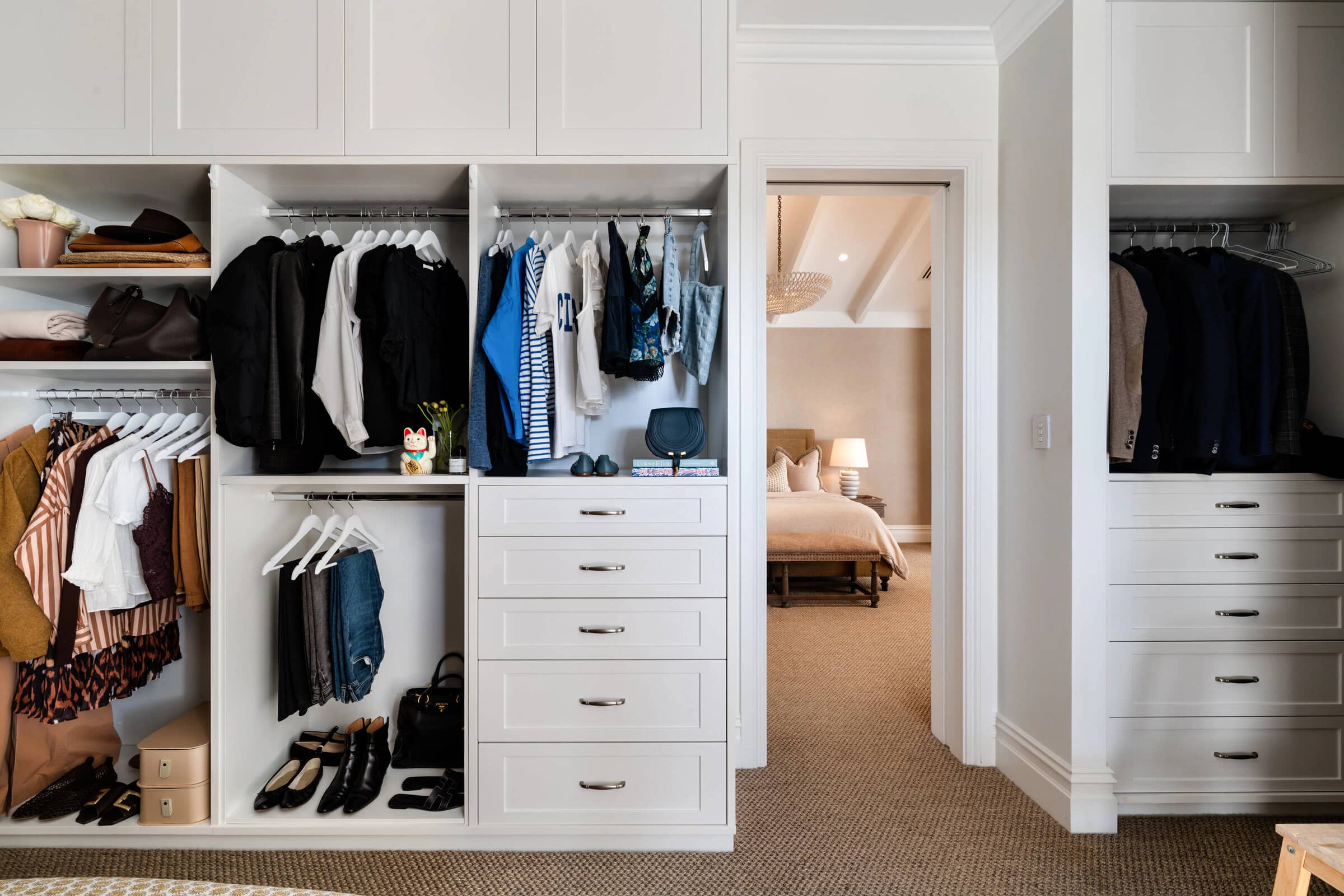 A wide, edited wardrobe with hanging clothes, folded knits and shoes in neat rows
